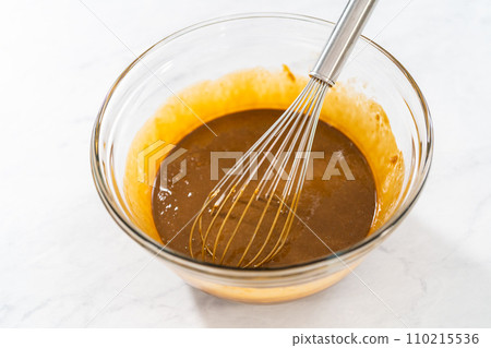 Mixing wet ingredients in a small glass mixing bowl to bake gingerbread bundt cake with caramel filling Mixing wet ingredients in a small glass mixing bowl to bake gingerbread bundt cake with caramel filling 110215536