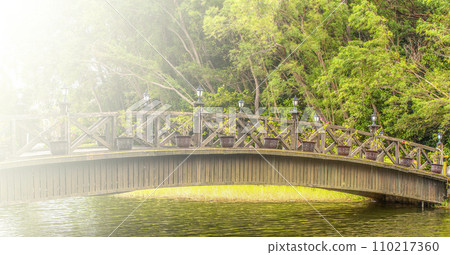 Beautiful wooden bridge across river on soft sunlight Beautiful wooden bridge across river on soft sunlight 110217360