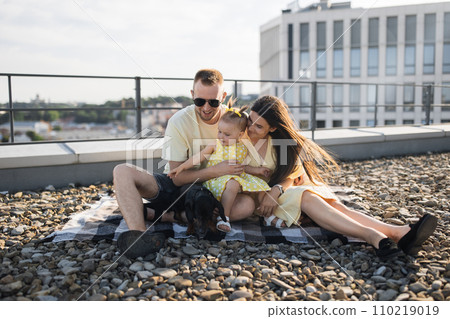 Joyful spouses having fun with daughter and dog on roof 110219019