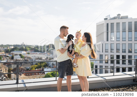 Pleased family and dog standing together on roof of building 110219098