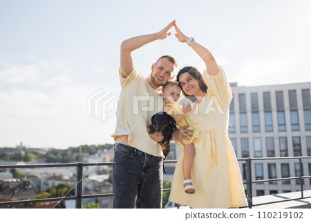 Family with raised up hands in form of house on city rooftop Family with raised up hands in form of house on city rooftop 110219102