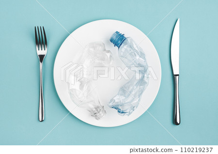 Bottle on the plate and other plastic waste on blue background 110219237