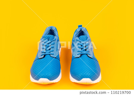 pair of comfortable blue sport shoes on yellow background, sportswear 110219700