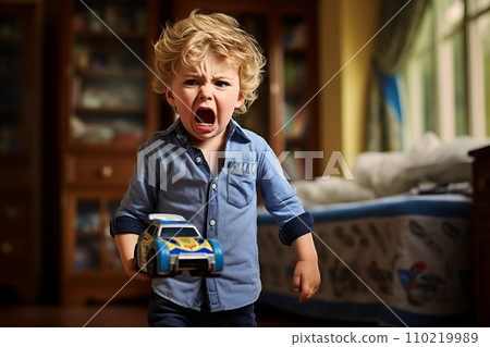 frustrated boy holds broken toy car in his hands, against the background of childrens room frustrated boy holds broken toy car in his hands, against the background of childrens room 110219989