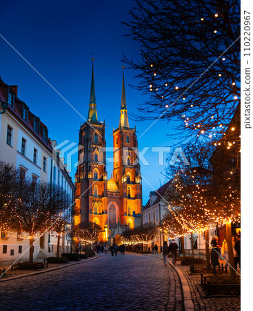 Street with cobblestone road, lights on trees, St. John the Baptist Cathedral, Wroclaw, Poland 110220967