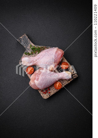 Raw chicken legs with salt, spices and herbs on a dark concrete background 110221409