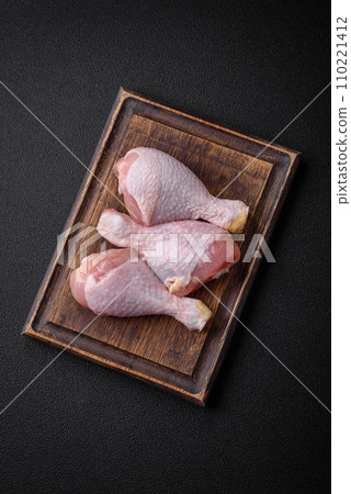 Raw chicken legs with salt, spices and herbs on a dark concrete background 110221412
