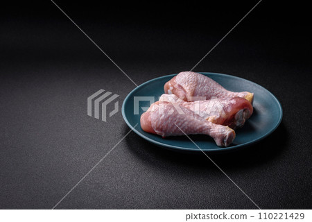Raw chicken legs with salt, spices and herbs on a dark concrete background 110221429