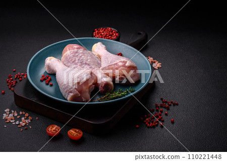 Raw chicken legs with salt, spices and herbs on a dark concrete background 110221448