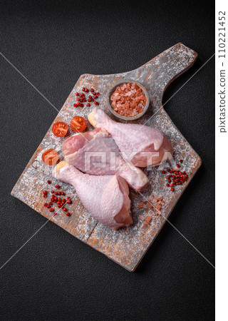Raw chicken legs with salt, spices and herbs on a dark concrete background Raw chicken legs with salt, spices and herbs on a dark concrete background 110221452