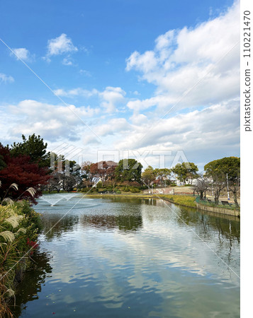 A park with blue skies, a pond, and a fountain A park with blue skies, a pond, and a fountain 110221470