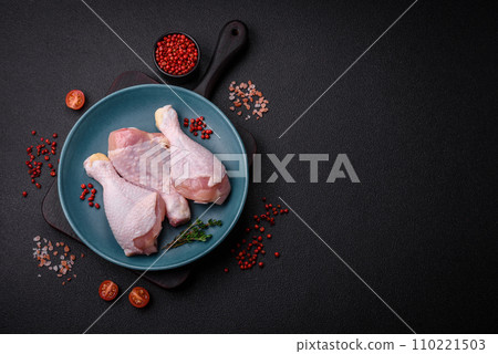 Raw chicken legs with salt, spices and herbs on a dark concrete background 110221503