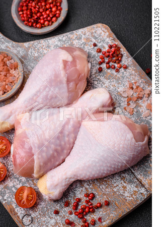 Raw chicken legs with salt, spices and herbs on a dark concrete background Raw chicken legs with salt, spices and herbs on a dark concrete background 110221505