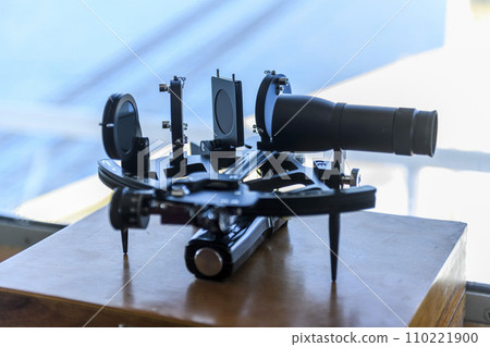 Nautical black sextant placed on wooden box in navigational bridge. Navigational equipment. Celestial navigation. Nautical black sextant placed on wooden box in navigational bridge. Navigational equipment. Celestial navigation. 110221900