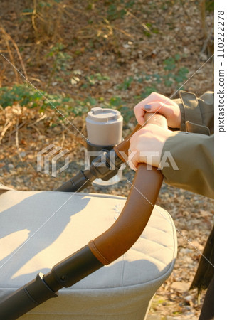 Hands pushing stroller with coffee mug, Germany Hands pushing stroller with coffee mug, Germany 110222278