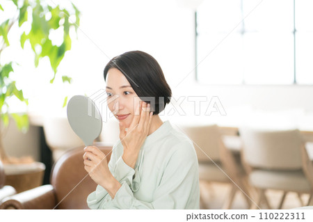一個30多歲的女人看著鏡子裡自己的臉 一個30多歲的女人看著鏡子裡自己的臉 110222311