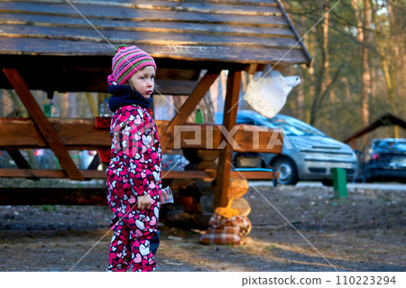 Preschool girl in red overalls at an autumn spring picnic Preschool girl in red overalls at an autumn spring picnic 110223294