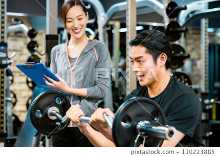 A man receiving guidance from a trainer at a fitness gym 110223885