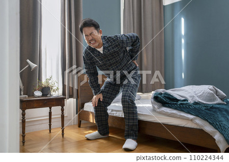 Image of middle-aged and elderly man in pajamas with back pain and strained back 110224344