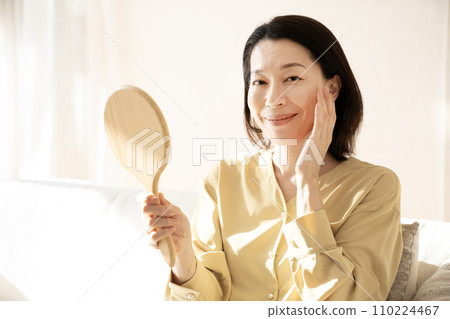 一個憂心忡忡的女人在沙發上照鏡子 110224467