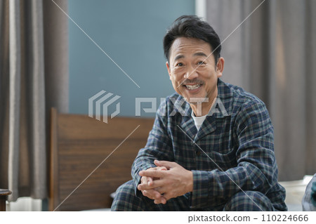 一名 50 多歲的男子穿著睡衣對著鏡頭微笑 110224666