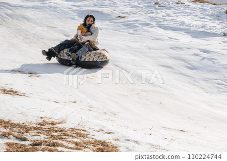 happy woman mother with child son tubing on slide in winter with snow happy woman mother with child son tubing on slide in winter with snow 110224744
