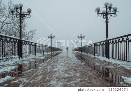 silhouette man maniac walks on foggy bridge with lanterns in winter with snow and fog silhouette man maniac walks on foggy bridge with lanterns in winter with snow and fog 110224974