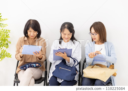 Woman filling out a clipboard in the waiting room 110225084