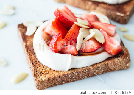 Crispy breakfast toast with ricotta, strawberries and almonds on white marble background. Crispy breakfast toast with ricotta, strawberries and almonds on white marble background. 110226159