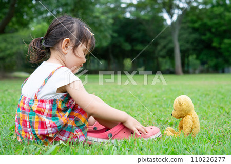 little girl playing with a teddy bear 110226277