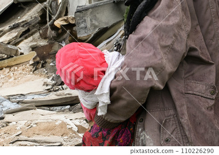 Mother with children near a destroyed house 110226290
