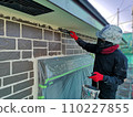 A male craftsman paints the exterior walls of a house using a multi-color method. 110227855