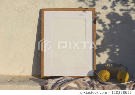 Neutral vertical wooden frame picture mockup against white old textured white wall in sunlight. Fresh yellow lemons fruit, cup of coffee. Mediterranean summer background with light, floral shadows. 110228632