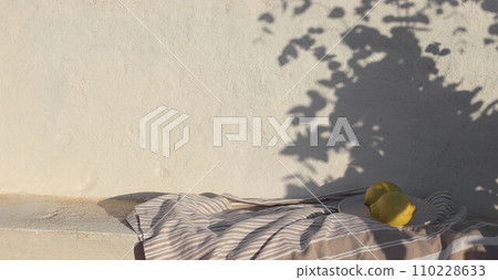 Mediterranean summer still life. Fresh lemons fruit in sunlight, floral foliage shadows overlay. White shabby old textured wall background. Cotton throw, blanket. Elegant neutral banner, vacation Mediterranean summer still life. Fresh lemons fruit in sunlight, floral foliage shadows overlay. White shabby old textured wall background. Cotton throw, blanket. Elegant neutral banner, vacation 110228633