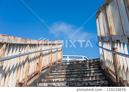 A dilapidated and rusty pedestrian bridge 110228656