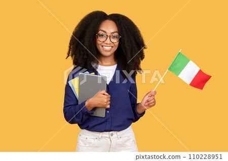 Smiling black lady student with Italian flag, enjoy exchange study, courses, isolated on yellow background 110228951