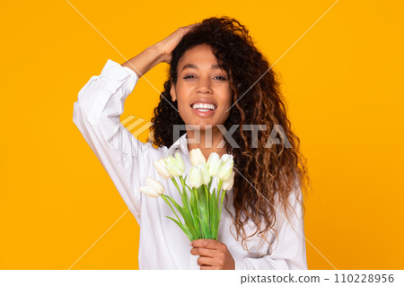 Happy young black lady holds bouquet of white tulips, studio Happy young black lady holds bouquet of white tulips, studio 110228956