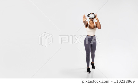 Sporty black lady experiencing virtual reality training on white backdrop Sporty black lady experiencing virtual reality training on white backdrop 110228969