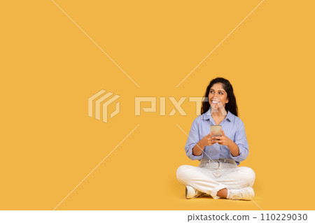 A relaxed young woman with curly hair, dressed in a blue shirt and white pants A relaxed young woman with curly hair, dressed in a blue shirt and white pants 110229030