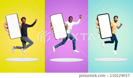 Joyful Young Men Jumping With Big Blank Smartphone In Hands Above Platforms 110229037