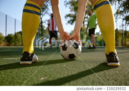 Soccer ball and sportsman legs over grass football field 110229332