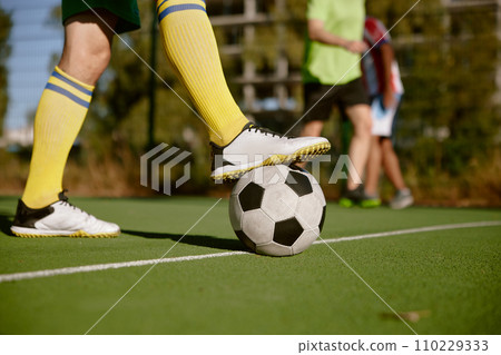 Closeup male foot in boots on soccer ball over green grass field Closeup male foot in boots on soccer ball over green grass field 110229333