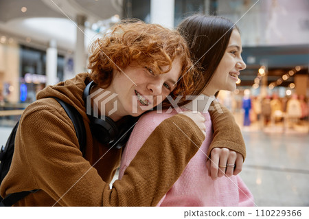 Portrait of loving teenage couple hugging while spending time at shopping mall 110229366