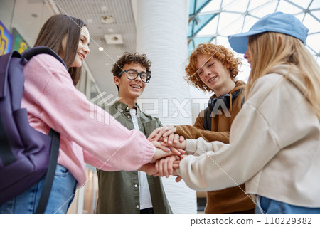Teenagers happy friends standing in circle putting hands together Teenagers happy friends standing in circle putting hands together 110229382