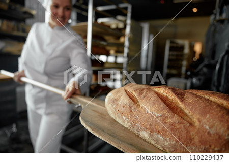 Closeup view on freshly baked artisan bread on shovel in female baker hands 110229437