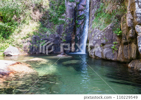 Picturesque Pincaes waterfall with a natural emerald pool located in a peaceful forest area, Peneda Geres National park, North Portugal 110229549