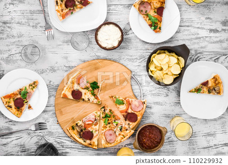dinner with pieces of pizza on board and plates dinner with pieces of pizza on board and plates 110229932