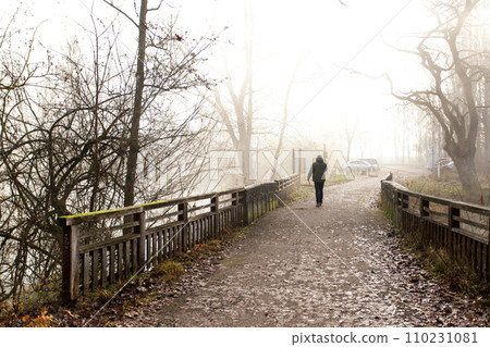 The man goes along the bridge in the fog to the car 110231081