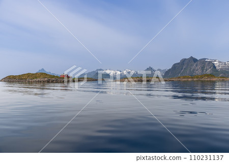 A solitary red Rorbu on Lofoten, Norway, with sea reflecting the clear sky and snowy peaks A solitary red Rorbu on Lofoten, Norway, with sea reflecting the clear sky and snowy peaks 110231137