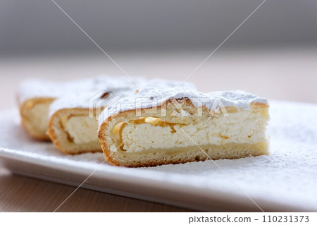 cheesecake curd strudel sliced on white plate sprinkled with powdered sugar dough is separated from curd creating drawing place for text advertising benefits of cooking show recipes restaurant serving 110231373